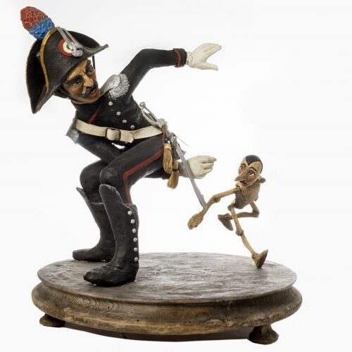 Gruppo raffigurante carabiniere con Pinocchio. In legno e terracotta dipinti recanti vestiti in stoffa. H 30 cm.