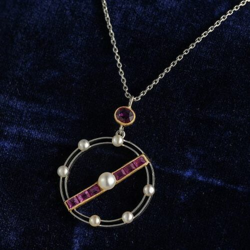 Collana girocollo in oro bianco e oro giallo recante pendente circolare con rubini e microperle naturali. Italia, Epoca Art Deco