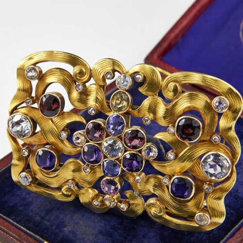 Grande broche in oro giallo 18 kt. lavorata a colpi di frusta e impreziosita da ametiste e quarzi nelle tonalità del viola. Russia, inizi '900