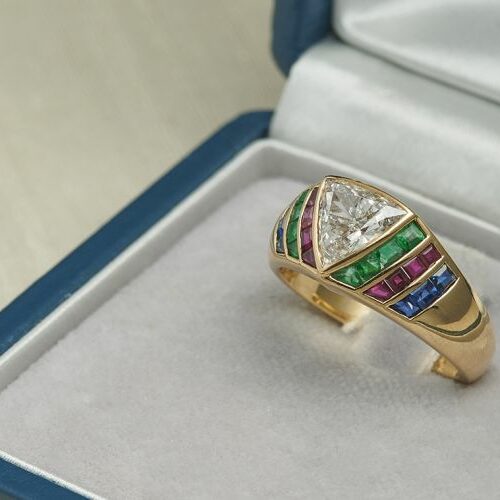 Anello oro giallo con 1 diamante triangolare ct. 1,30 ca, smeraldi, zaffiri e rubini carrè. Firmato Illario.